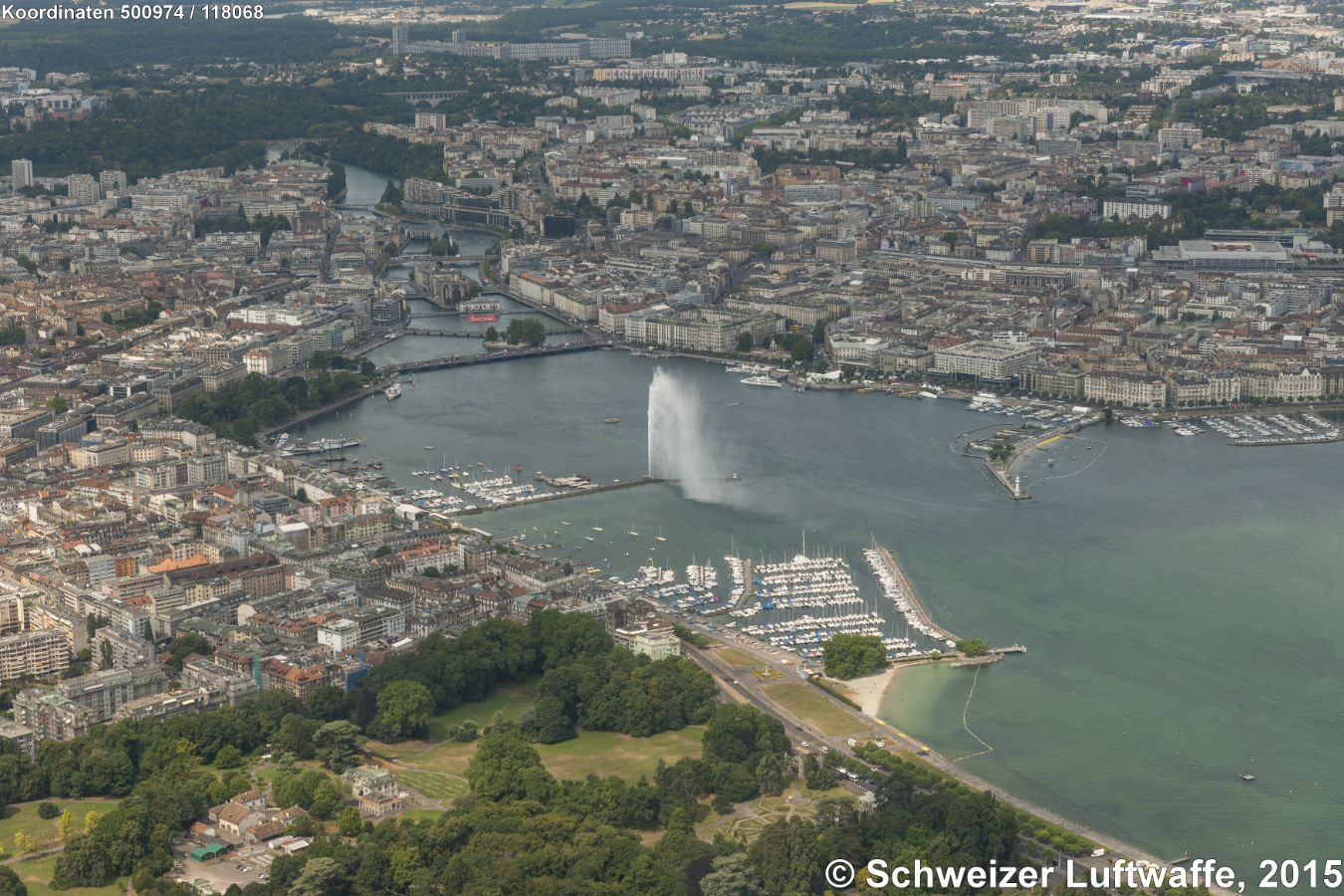 Genf / Genève, Seebecken, 'Jet d'eau' (Position: 2'500'996.71, 1'118'130.85) Blick Richtung Westen Rhone-abwärts zur 'Ile Rousseau' Im Vordergrund links: Stadtteil Eaux-Vives, vorgelagert Pärke 'La Grange' und 'des Eaux-Vives'. Hinten Mitte: Stadtteil St-Gervais, Bahnhof SBB/SNCF. Bildmitte rechts im See: Plage und 'Le Phare de Genève'.